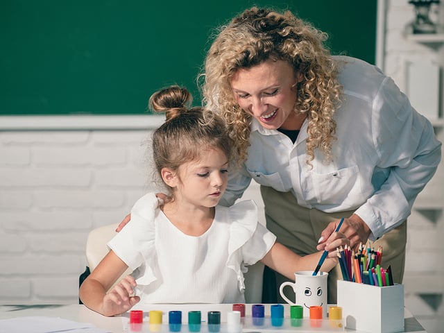 female teacher helping young girl school.jpg