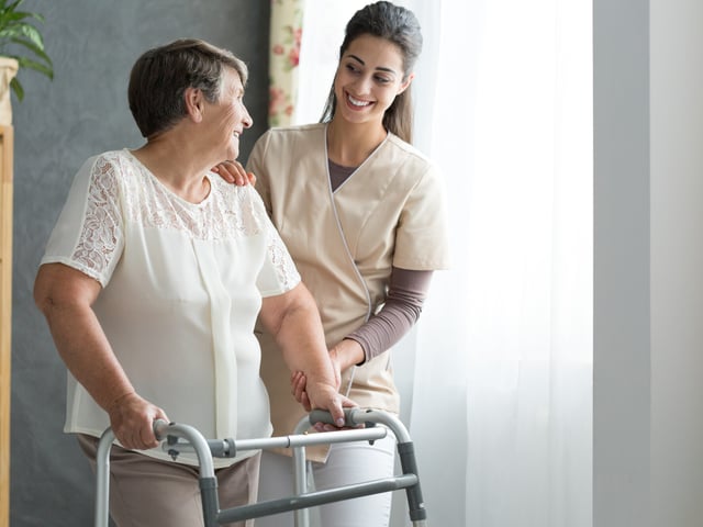 smiling nurse helping woman with walker.jpg
