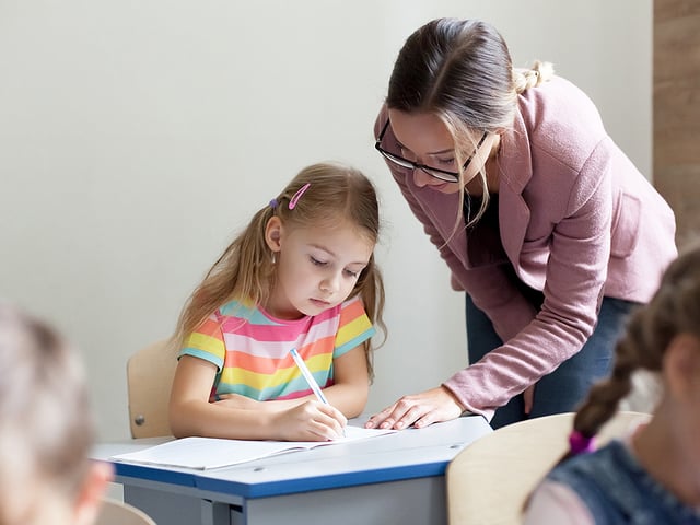 female teacher helping young child.jpg